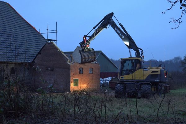 De kraan sloopt de melkschuur.