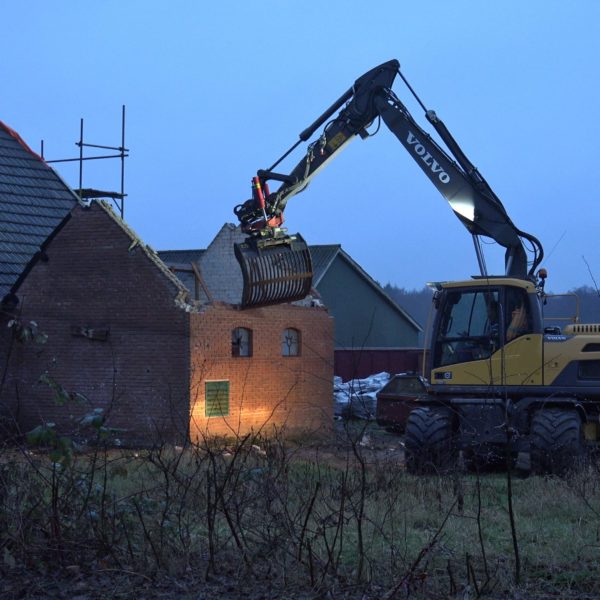 De kraan sloopt de melkschuur.