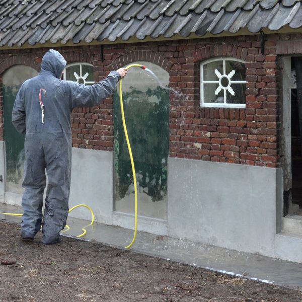 Hennie reinigt de westgevel van de schuur.