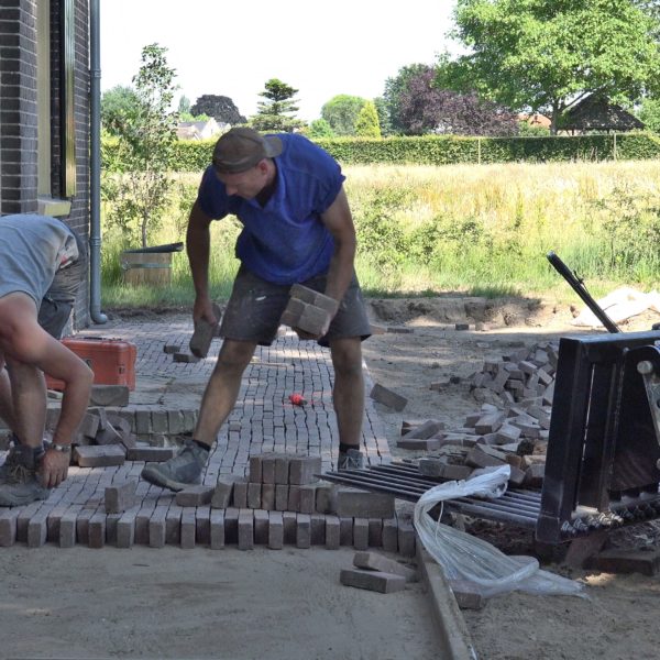 Wes en Kees leggen een terras voor het huis aan.