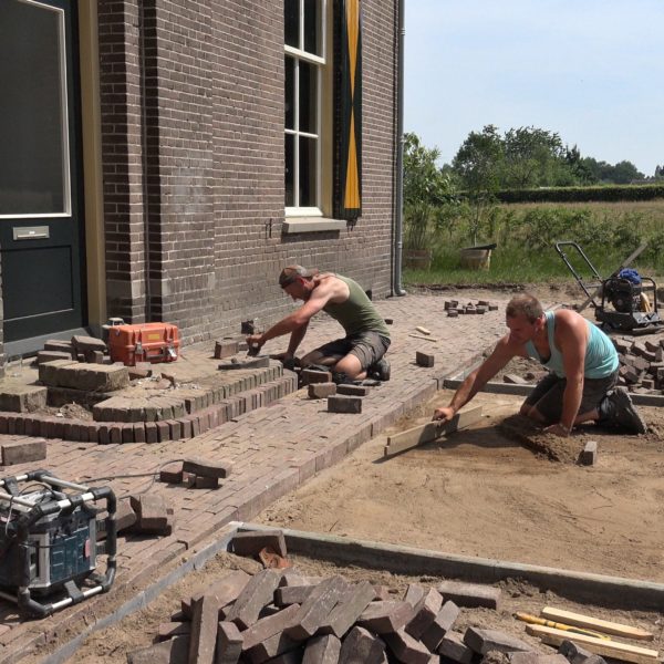 Wes en Kees leggen een terras voor het huis aan.